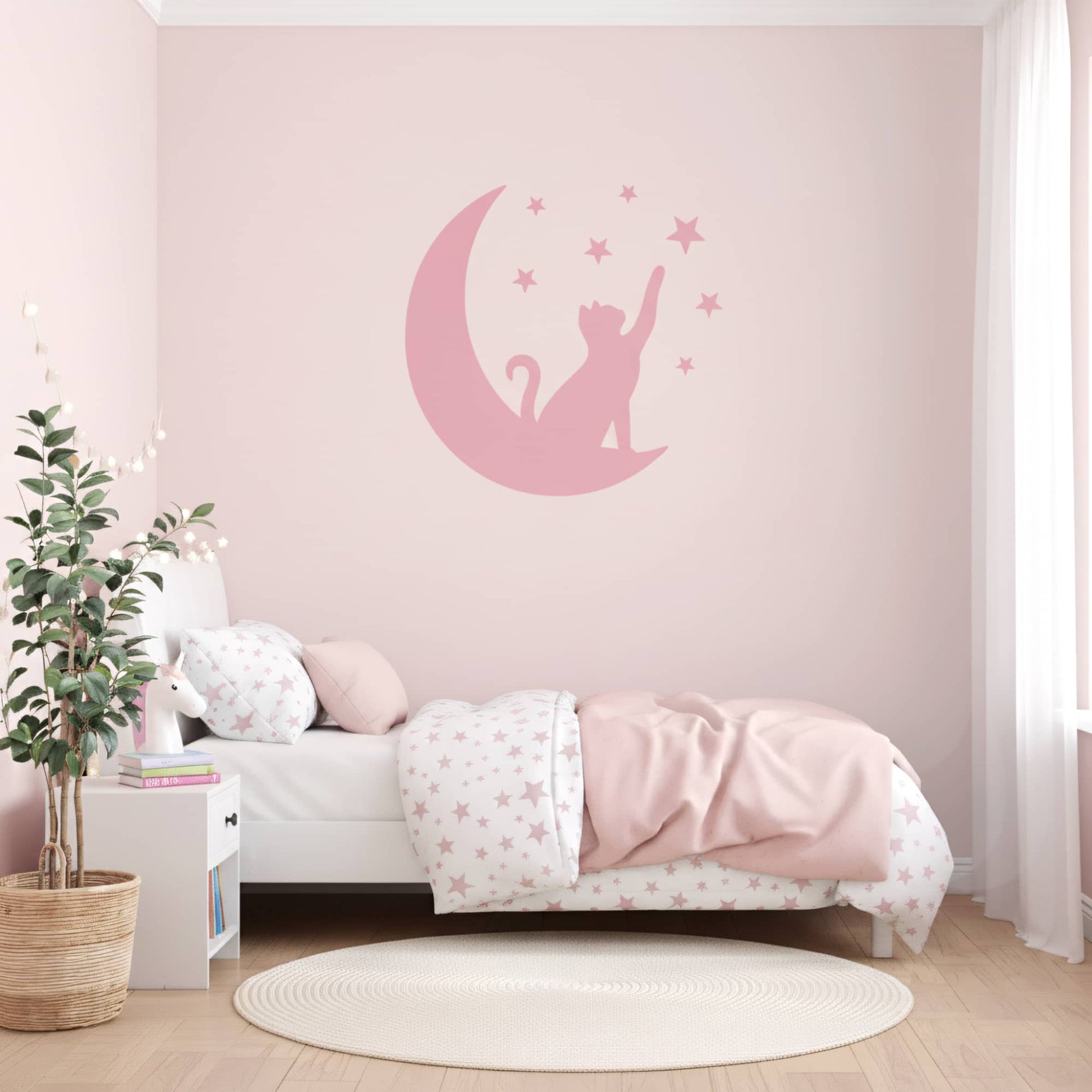 Une chambre fille avec des murs peints en rose et un grand sticker mural de Chat Lunaire rose, créant une ambiance harmonieuse pour la décoration chambre enfant au Maroc.