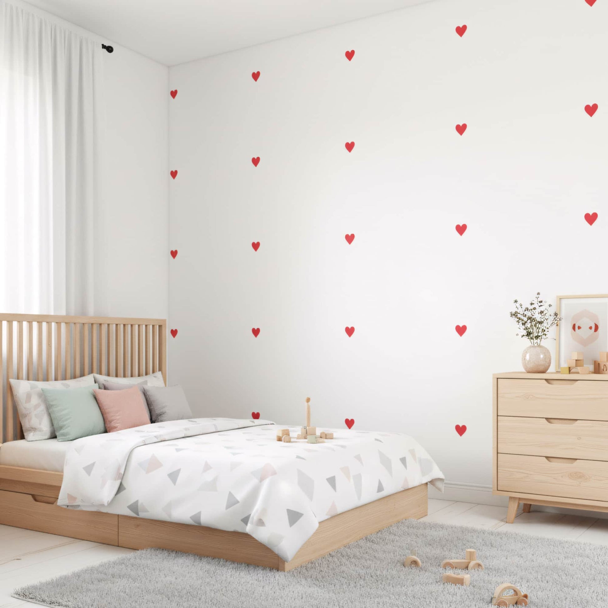 Un lit en bois dans une chambre d'enfant mise en valeur par des stickers cœurs rouges amour, une décoration murale simple et chaleureuse au Maroc.