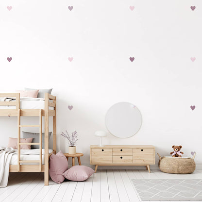 Un miroir rond et des stickers cœurs teintes violet sur un mur blanc, une décoration murale qui allie style et modernité dans une chambre de fille au Maroc.