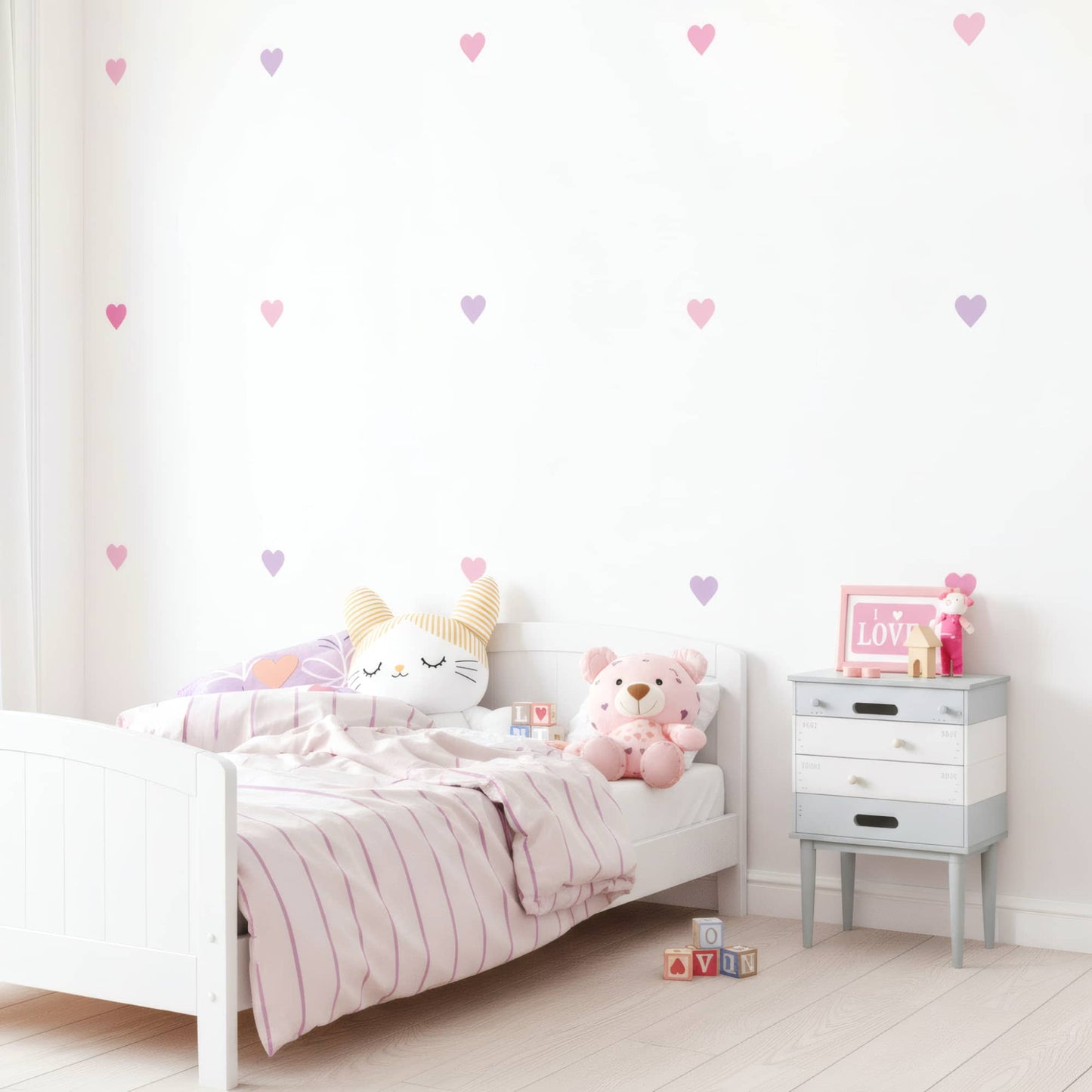 Lit blanc d'enfant mis en valeur par des stickers muraux cœurs rose bonbon, ajoutant une touche d'amour et de couleur à la chambre au Maroc.