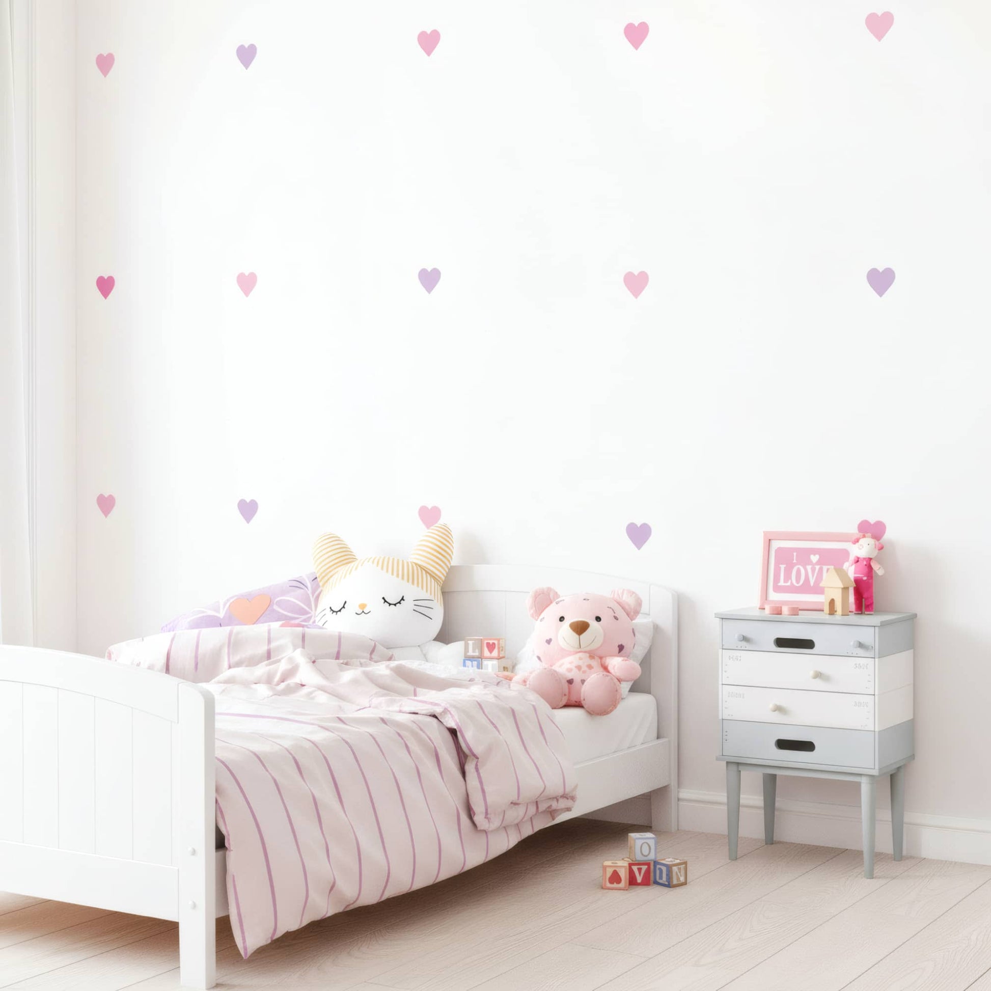 Lit blanc d'enfant mis en valeur par des stickers muraux cœurs rose bonbon, ajoutant une touche d'amour et de couleur à la chambre au Maroc.