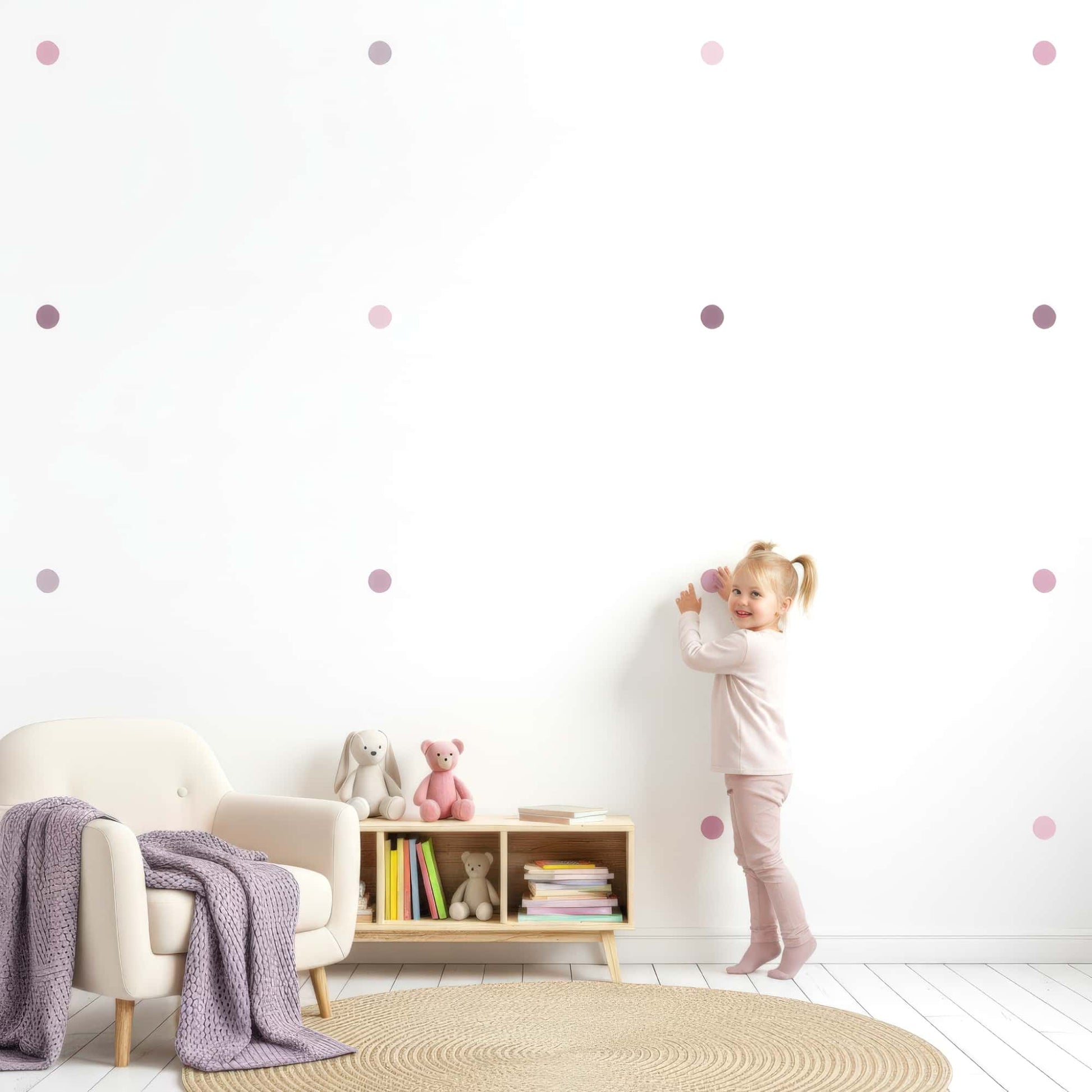Une petite fille s'amuse à poser des stickers pois teintes violet sur un mur, montrant l'aspect ludique et la facilité de cette décoration murale pour la chambre enfant au Maroc.