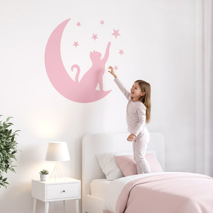 Une fillette se tenant debout sur son lit, jouant avec un grand sticker animaux du Chat Lunaire rose. Un élément décoratif pour une chambre enfant au Maroc.