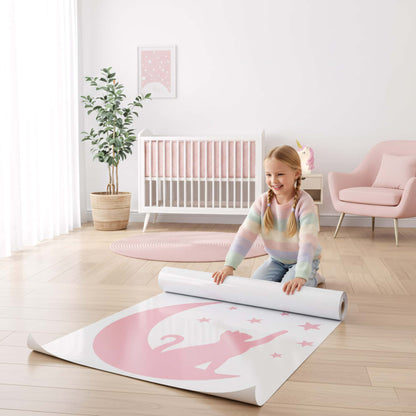 Fillette assise sur le sol déroulant un rouleau de stickers muraux du Chat Lunaire rose, un accessoire simple pour une décoration chambre bébé ou enfant au Maroc.