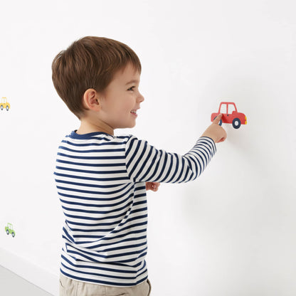Gros plan sur un enfant dans une chambre décorée, pointant un sticker mural voiture rouge. Idéal pour une décoration chambre enfant ludique au Maroc. Stickers de décoration murale faciles à appliquer. Multicolore