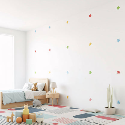 Stickers étoiles multicolores dispersés sur un mur blanc, créant une ambiance de ciel étoilé et joyeuse pour la décoration murale de chambre de bébé au Maroc.