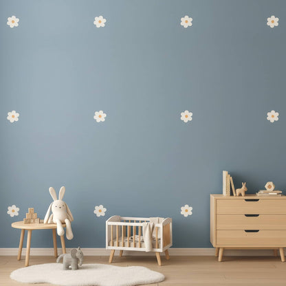 Une décoration murale avec des stickers fleurs marguerites beiges sur un mur bleu, créant un contraste doux et apaisant pour la chambre de bébé.