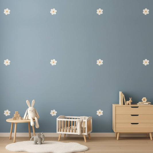Une décoration murale avec des stickers fleurs marguerites beiges sur un mur bleu, créant un contraste doux et apaisant pour la chambre de bébé.