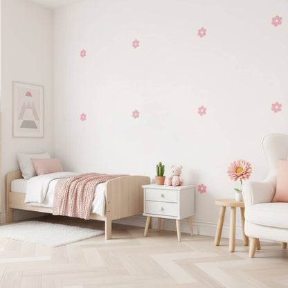 Un lit en bois et un tapis douillet dans une chambre d'enfant, mis en valeur par des stickers fleurs marguerites roses. Une décoration murale qui rend l'espace chaleureux et élégant au Maroc.