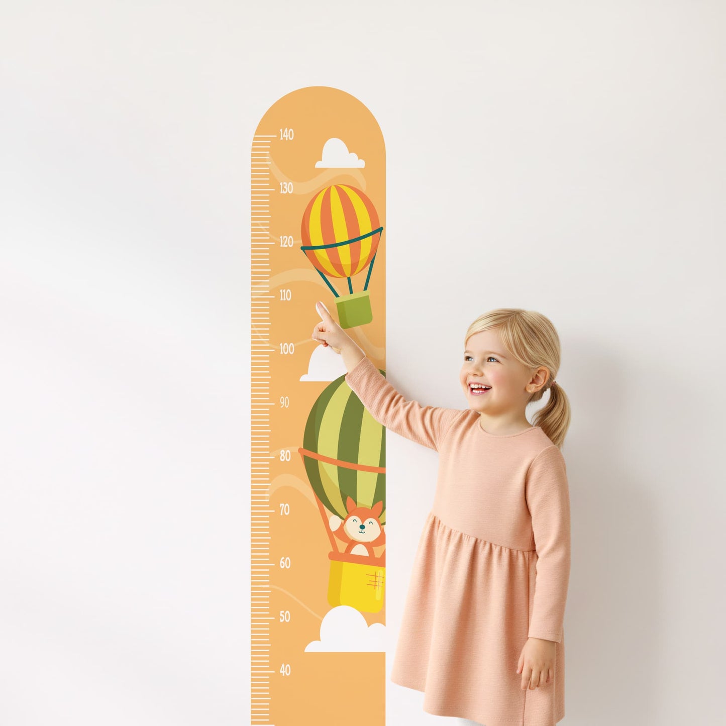 Petite fille souriante pointant la toise stickers muraux Montgolfières. Décoration chambre enfant Maroc.