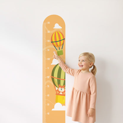 Petite fille souriante pointant la toise stickers muraux Montgolfières. Décoration chambre enfant Maroc.